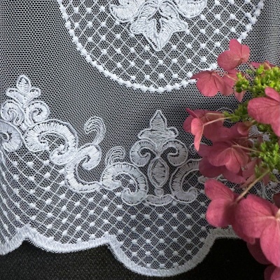 Stylish white curtain with embroidered ornamental pattern at the bottom 